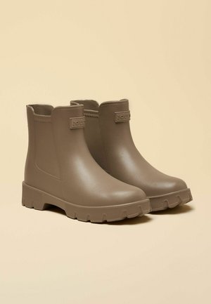 Braune wasserdichte Stiefeletten mit glatter Oberfläche, elastischen Seitenteilen und einer strukturierten Gummisohle mit tiefem Profil für guten Halt.