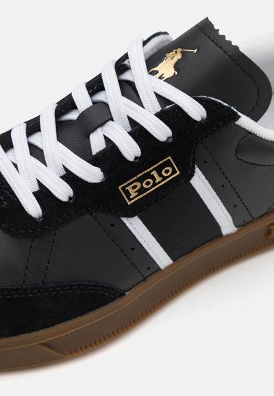 Zwarte leren sneaker met suède accenten, witte strepen, gouden logo en witte veters. Beschikt over een rubberen zool en geperforeerde details aan de zijkant.