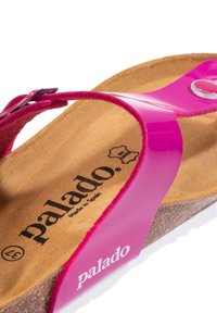 Infradito rosa con cinturino in pelle verniciata, soletta in sughero e suola in gomma bianca. Presenta logo e accento metallico sul cinturino.