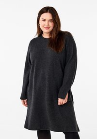 Mörkgrå, löst sittande stickad klänning i mjukt material, med lång ärm, rund halsringning och sidslitsar vid nederkanten.