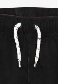 Svarte shorts med elastisk midje og hvit snor, detaljert med et diamantmønster på spissene. Glatt stofftekstur.