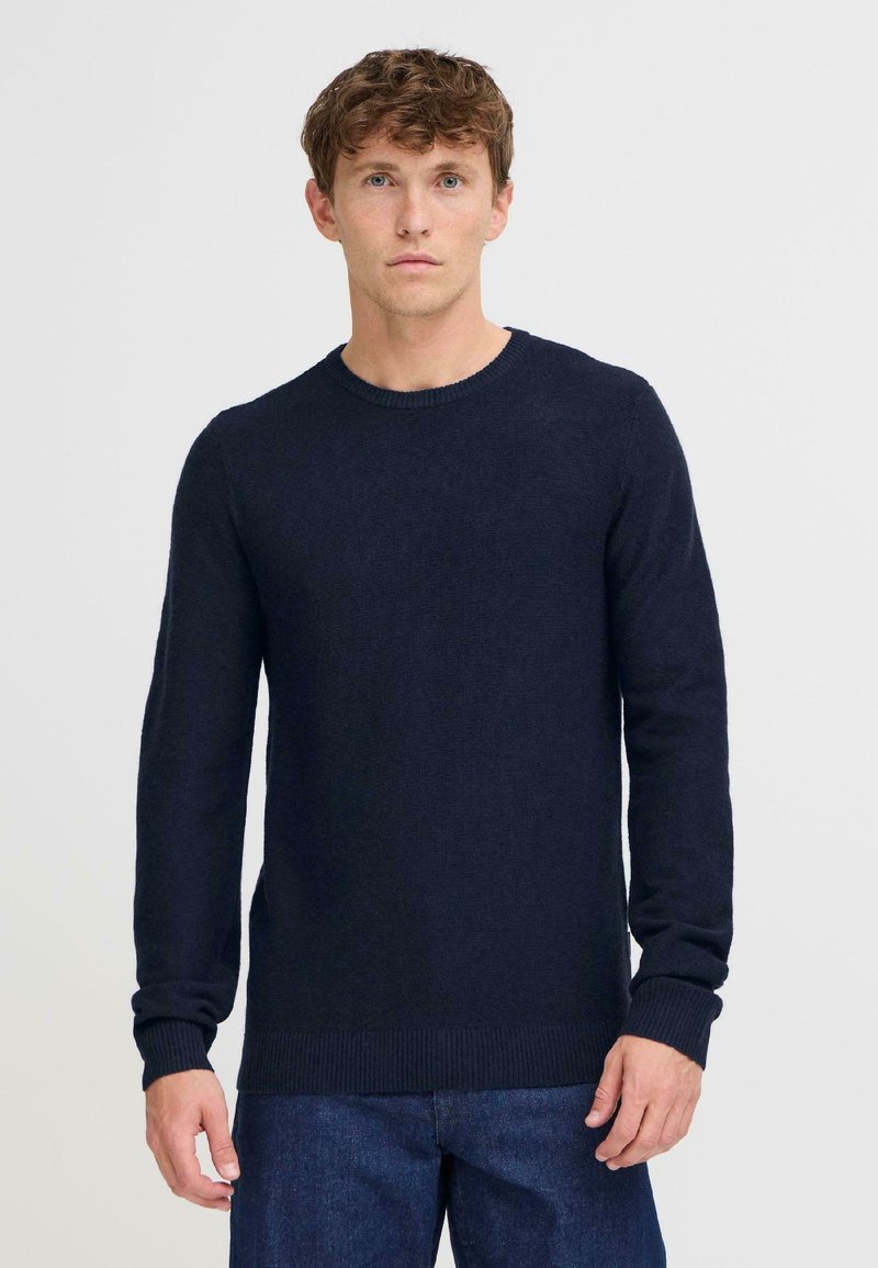 Marineblauwe gebreide trui met lange mouwen, ronde halslijn en geribbelde manchetten. Zachte textuur, casual pasvorm, ontworpen voor comfort.