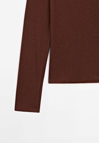 Bordeaux lange mouwen top van zachte stof, met een getailleerde snit en een nette zoom. Geen zichtbare patronen of hardware details.