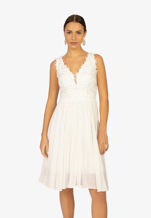 White dress featuring a floral lace bodice, V-neckline, and pleated skirt. The fabric is lightweight, with a knee-length design.