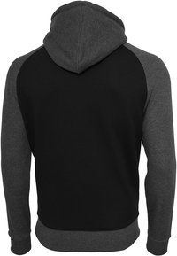 Majica s kapuljačom crne boje s tamnosivim raglan rukavima. Ima mekanu teksturu i uski donji rub, bez vidljivih logotipa.