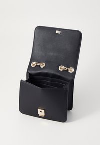 Schwarze Lederbörse mit glatter Oberfläche, ausgestattet mit einem magnetischen Klappverschluss, goldfarbener Hardware und mehreren Kartenfächern im Inneren.