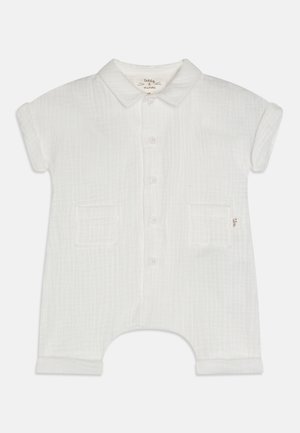 Hvid bomuldsromper med korte opkrøllede ærmer, knaplukning foran, to forlommer og en diskret tekstureret mønster over det hele.