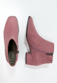 Stivaletti alla caviglia in pelle scamosciata rosa polvere con punta arrotondata, chiusura laterale con zip e tacco a blocco basso. Caratterizzati da una texture liscia e cuciture minimaliste.