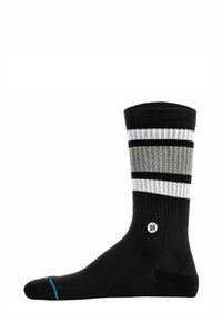 Schwarze Socke mit vertikalen Streifen in Grau und Weiß, gerippter Textur am oberen Teil, mit einem Logodetail nahe dem Knöchel und blauen Akzenten an der Zehe.