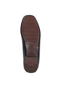 Chaussure en cuir noir avec une semelle en caoutchouc brun texturé. Présente un bout arrondi et un petit accent rouge près du talon.