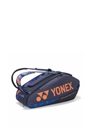 Bolsa deportiva Yonex en azul marino y azul con logo naranja, correas para llevar y múltiples compartimentos con cremallera diseñados para guardar raquetas.