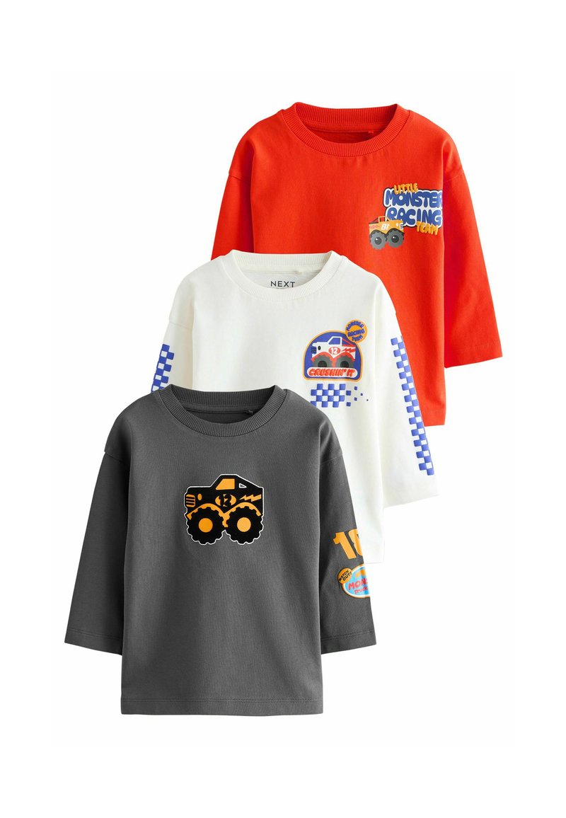 Tres camisetas de manga larga: roja con texto y gráfico, blanca con acentos azules y gráfico, gris con un diseño de camión monstruo audaz.