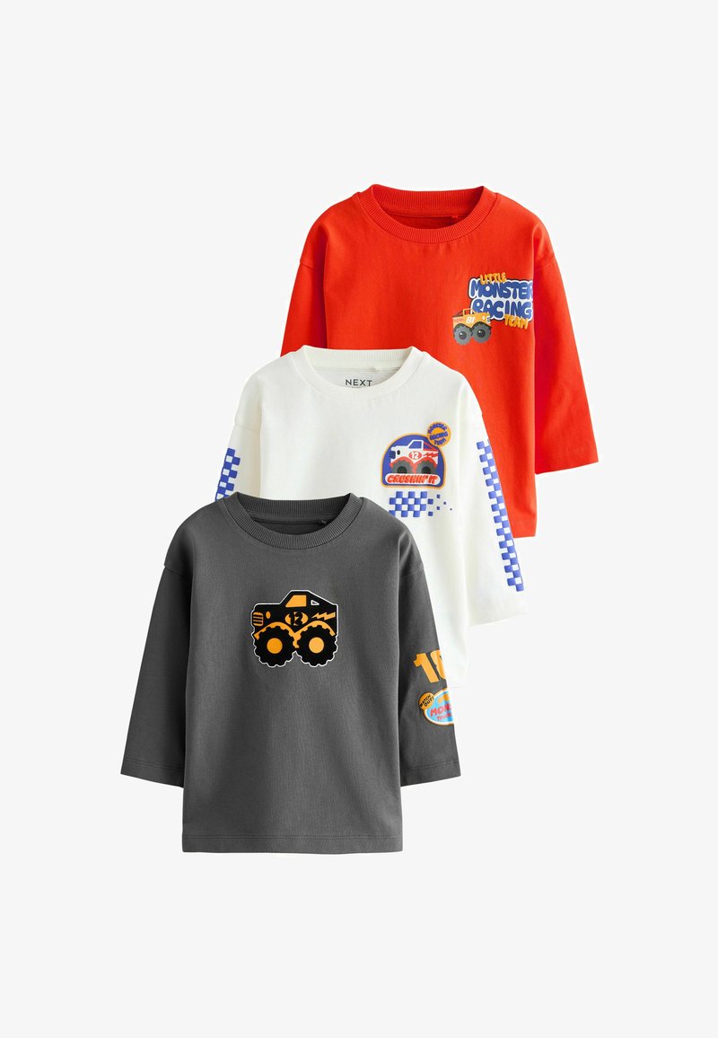 Tres camisetas de manga larga: roja con texto y gráfico, blanca con acentos azules y gráfico, gris con un diseño de camión monstruo audaz.