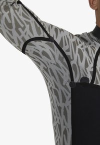 Long-sleeve garment featuring a black and gray abstract pattern, with contrasting black accents and circular hardware details.