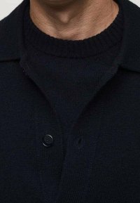 Marineblauer Strickcardigan mit strukturierter Oberfläche, ausgestattet mit Knopfleiste und klassischem Kragen. Glatter Stoff mit lockerem Schnitt.