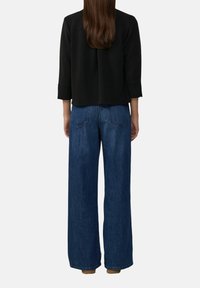 Zwarte top met driekwart mouwen, gecombineerd met brede, donkerblauwe denim jeans met achterzakken en een gladde textuur.
