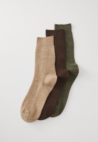 Tres pares de calcetines de caña corta con estrías en beige, marrón y verde oliva, dispuestos de manera superpuesta sobre un fondo blanco.