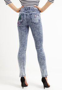 Wąskie dżinsy w jasnoniebieskim, przetartym deninie o gładkiej fakturze. Zawierają haftowane detale kwiatowe na tylnym kieszeni oraz wysoki stan.