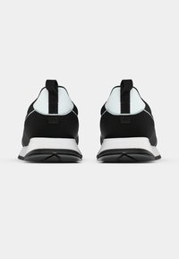 Crne sportske cipele s gornjim dijelom od glatkog tkanog materijala, kontrastnim svijetloplavim detaljima i bijelim potplatom s teksturiranim uzorkom.