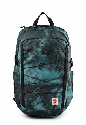 Türkis-schwarz gemusterter Rucksack mit elastischer Kordel vorne, Seitentaschen, oberem Tragegriff und kleinem rotem Fuchsemblem unten vorne.