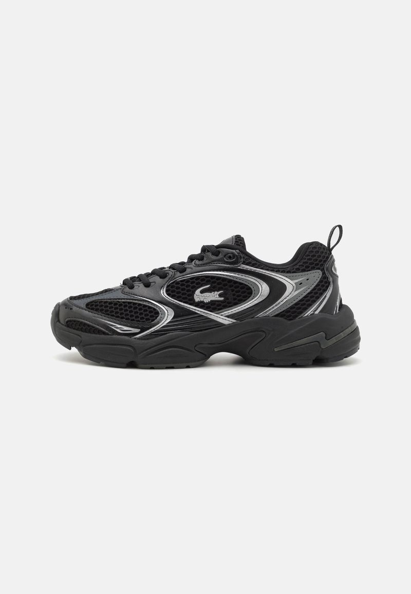 Baskets de sport noires avec panneaux en mesh, semelle épaisse, design à lacets, détails argentés et logo crocodile sur le côté.