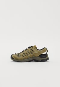 Green mesh hiking shoe with rubber toe cap, lace-up front, and pull tab. Features multiple ventilation cutouts and a rugged black sole.