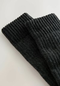 Sorte strikkede sokker med ribbestruktur. Materialet virker blødt og tykt, hvilket gør dem velegnede til varme og komfort.