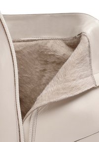 Interior de bolsa de cuero beige con un forro suave y texturizado en beige. Cuenta con un cierre de cremallera y costura limpia a lo largo del borde.