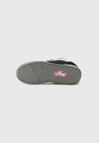 Must musta tekstuuriga halli kummitald, millel on valge aktsentriba ja silmapaistev "VANS" logo tald.