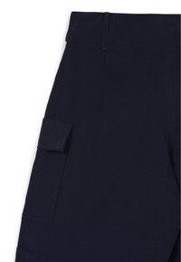 Pantaloni cargo blu marina con tasca laterale, texture liscia, vita piatta e cuciture rinforzate. La vista ravvicinata enfatizza i dettagli del design.