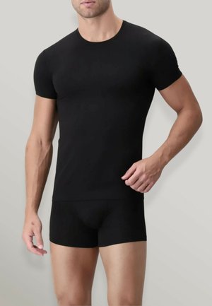 T-shirt nera aderente in tessuto elastico con scollatura a girocollo e maniche corte, abbinata a pantaloni boxer aderenti dello stesso colore.