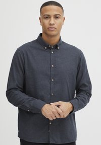 Dunkelblaue Denim-Hemd mit Kragen, langen Ärmeln und braunen Knöpfen, das eine glatte Textur und einen geraden Saum aufweist.