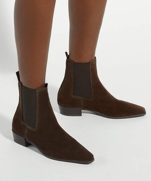 Bottines marron en daim avec panneaux latéraux élastiques et talons blocs bas, portées aux pieds sur un fond blanc uni.
