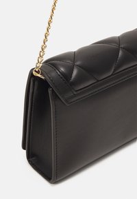 Svart läderhandväska med kviltad textur, utrustad med en guldkedjesläp och en strukturerad form; slät yta med skarpa hörn och kanter.