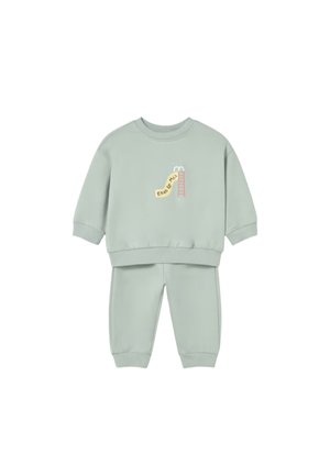 Completo felpa e pantaloni verde chiaro per bambino piccolo con piccolo disegno rosa di scivolo e scala e testo sul davanti della felpa.