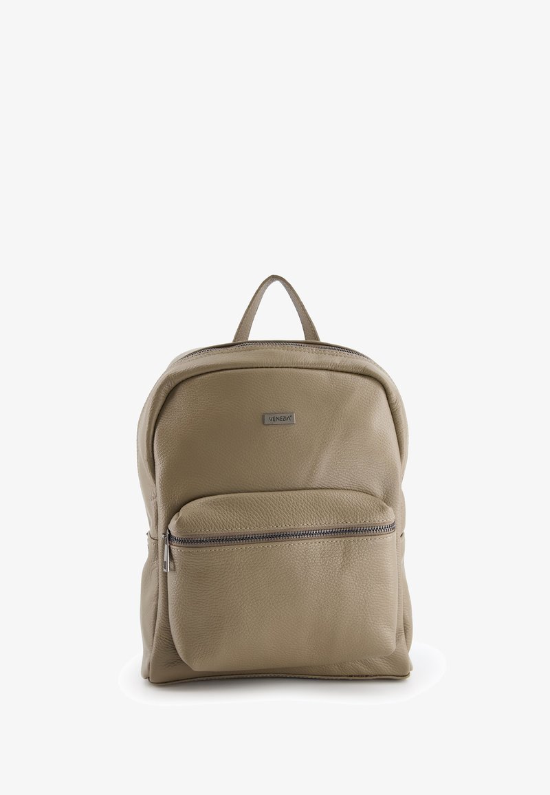 Sac à dos en cuir beige avec une poche zippée à l'avant, forme arrondie, poignée supérieure et une petite plaque logo sur le compartiment principal.