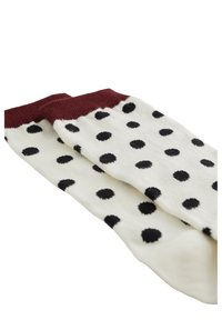 Chaussettes blanches avec un bord bordeaux, présentant un motif de pois noirs. Le tissu semble doux avec une texture lisse.