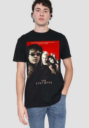 Man wearing black T-shirt with red and black graphic of six characters from "The Lost Boys" movie on the front.