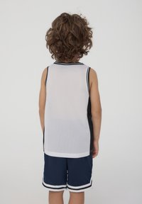 Canotta sportiva bianca in rete con accenti neri, abbinata a pantaloni corti in rete blu navy con strisce bianche all'orlo.
