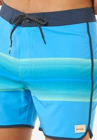 Pantaloni da bagno blu con un design sfumato che va dal blu chiaro al blu scuro, vita elastica con lacci neri e accentuazione del logo laterale.