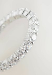 Bague en argent ornée de pierres claires rondes et ovales alternées, avec un anneau lisse et arrondi et une finition polie. Accents texturés entre les pierres.
