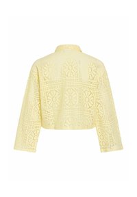 Veste en dentelle jaune clair avec motif floral ajouré, manches longues et coupe courte, vue de dos.