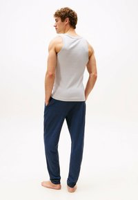 Szary bezrękawnik w połączeniu z granatowymi spodniami dresowymi, charakteryzującymi się luźnym krojem, miękką teksturą i bocznymi kieszeniami. Prosty design bez wzorów.