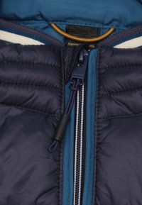 Marinekleurige gewatteerde jas met een rits aan de voorkant, blauwe voering en geribbelde kraag met witte strepen. Inclusief trekkoord aanpassingen bij de nek.