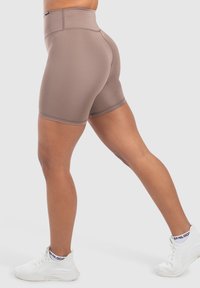 Pantaloni corti marroni a vita alta con una texture liscia e un design aderente. Finitura a metà coscia, con cuciture minime e una finitura pulita.
