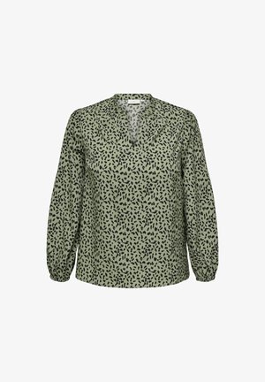 Zaļa blūze ar V-veida kakla izgriezumu un garām, elastīgām piedurknēm. Rakstā ir melns, izkliedēts leopardu raksts. Mīksta auduma tekstūra.