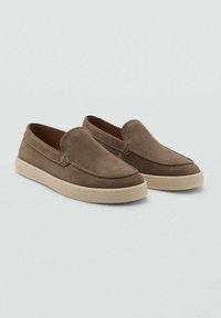 Braune Wildlederschlupfschuhe mit runder Spitze, gesteppten Details und einer kontrastierenden cremefarbenen Gummisohle. Glatte Textur, minimalistisches Design.