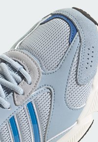 Light blue athletic shoe featuring mesh panels, suede accents, and textured overlays. White sole with black tread and blue detailing.