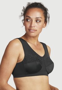 Musta rintaliivi kukkaketjuin, leveillä olkaimilla ja sileällä pinnalla. Varustettu kaaritukikupilla ja koristeellisella tikkaustyöllä reunoilla.