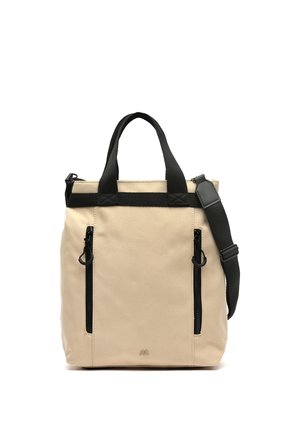 Bolsa tote de lona beige con dos bolsillos verticales con cremallera negra, doble asa negra y una correa de hombro negra ajustable.